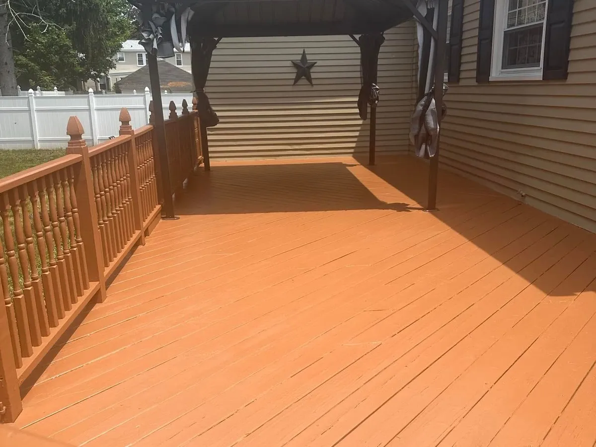 Backyard wood deck freshly stained terracotta orange with a hard-top gazebo